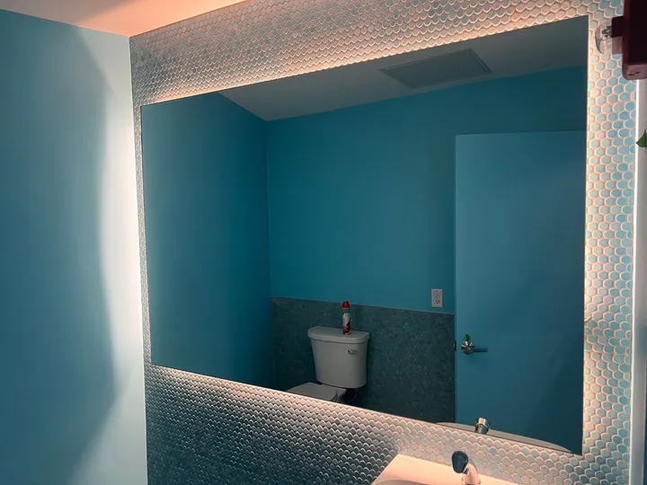 Backlit floating mirror installed in a tiled bathroom