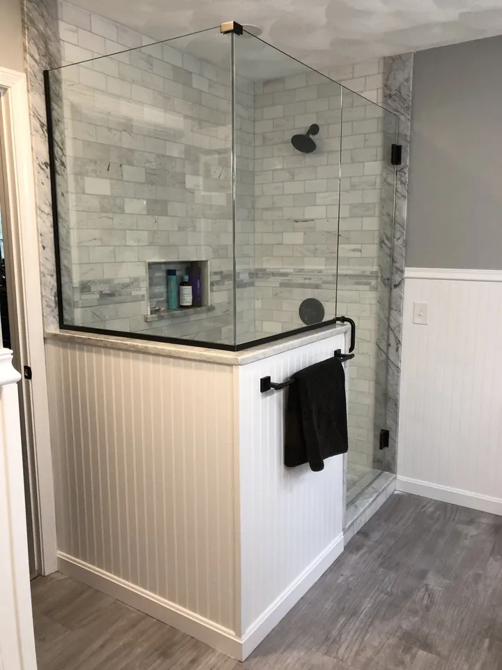 Corner glass shower enclosure in a tiled bathroom