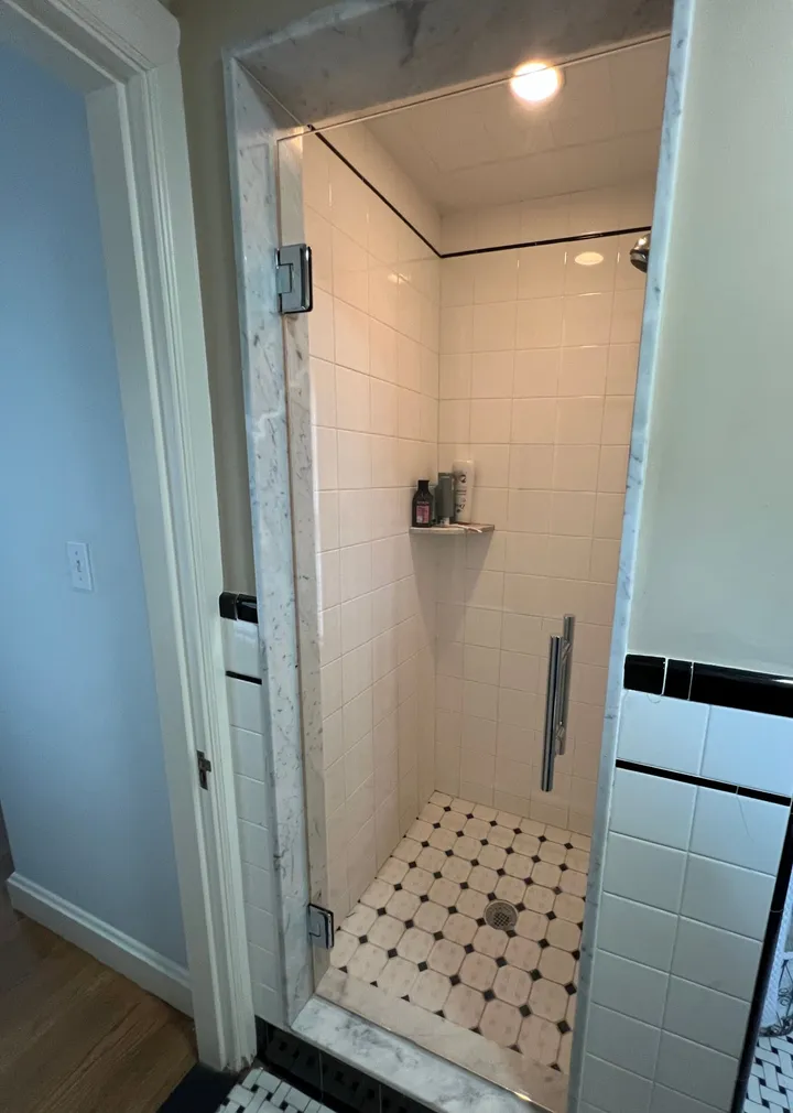 Clear frameless glass shower door in a tiled alcove