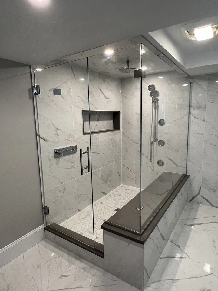 Frameless glass shower with a marble-look bench and recessed niche