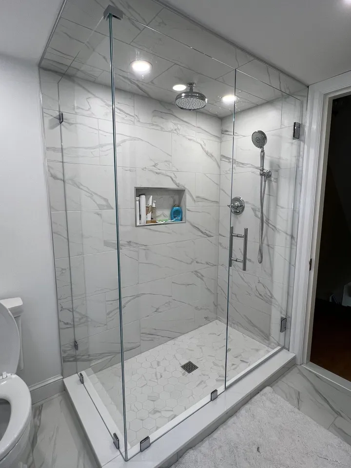 Frameless glass shower with marble walls and a niche