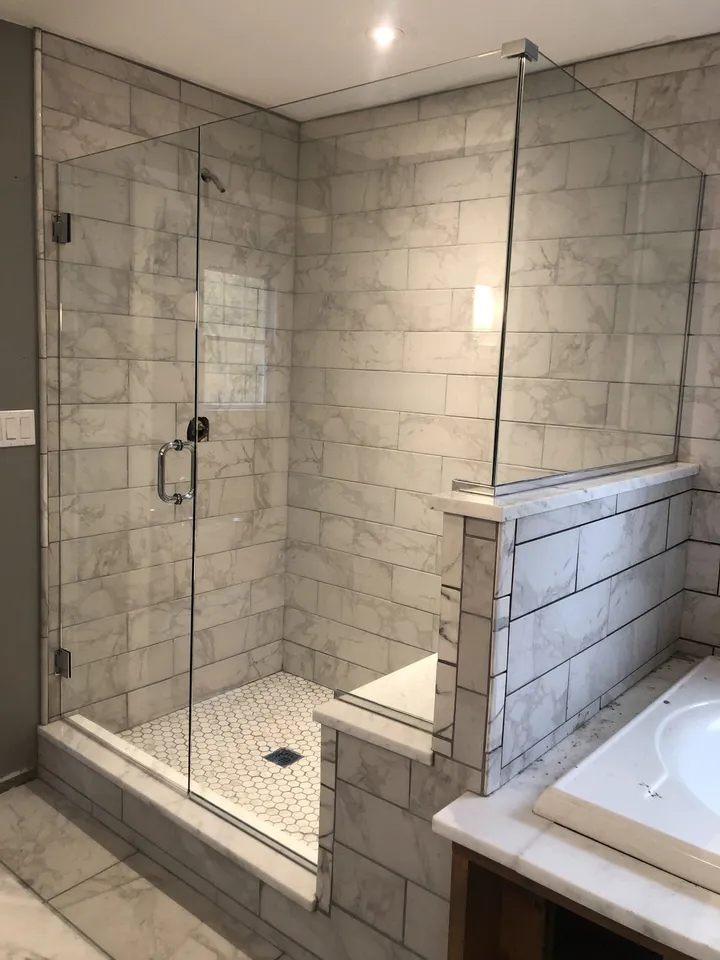 Marble walk-in shower with a frameless glass panel