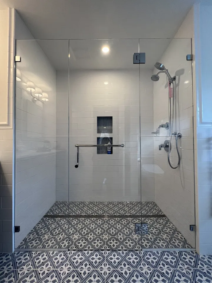 Frameless glass shower with a blue patterned tile floor