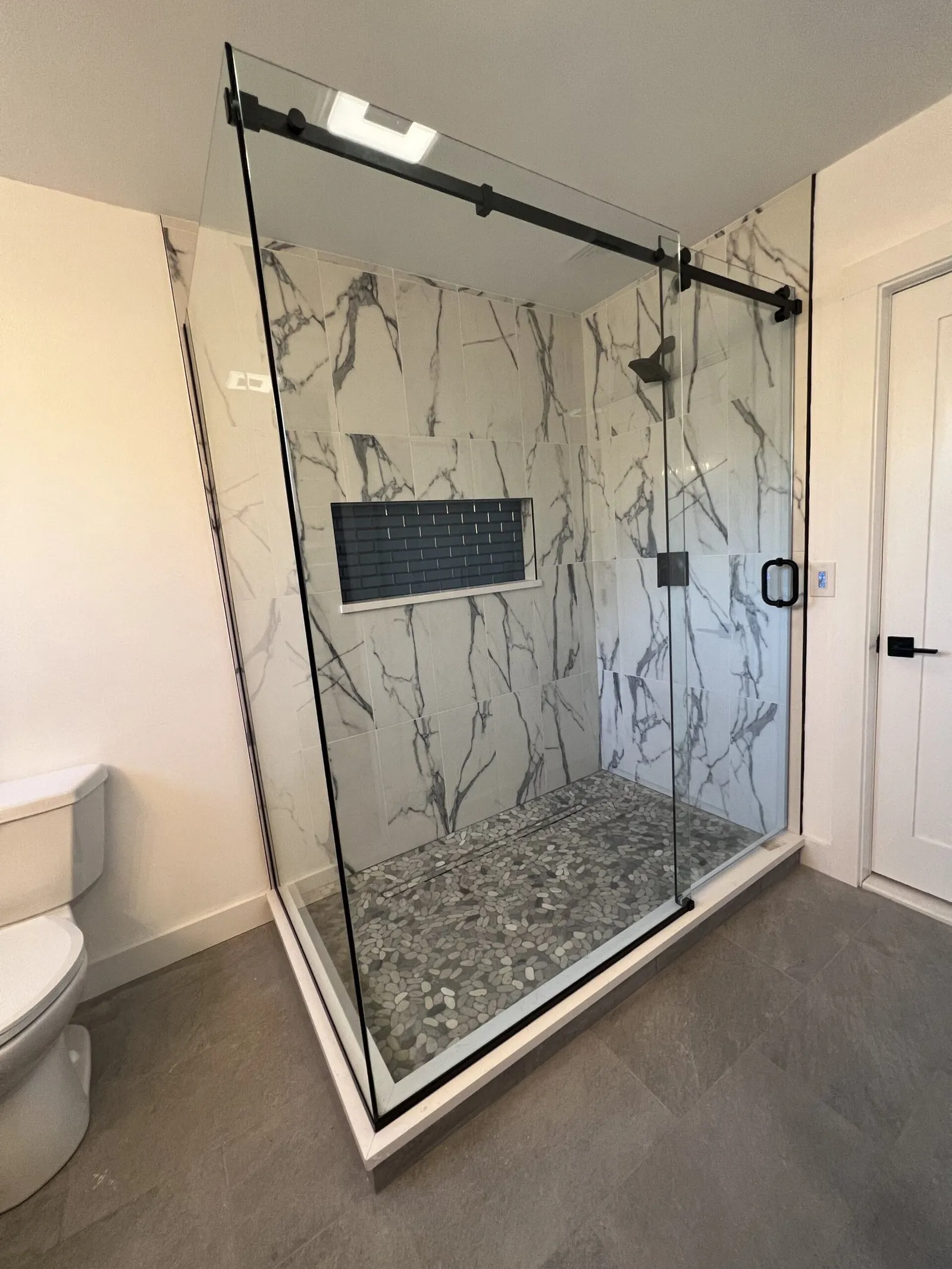 Frameless sliding glass shower door with marble-look tile