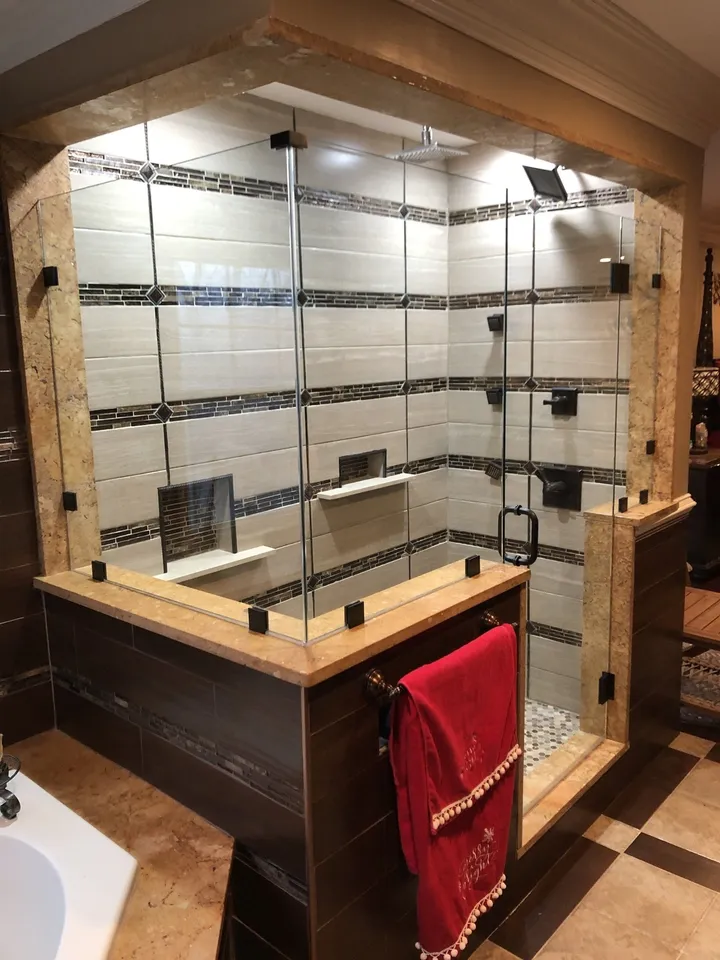 Large glass shower enclosure on a tiled knee wall with black hardware