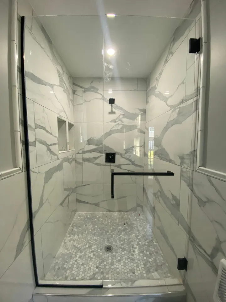 Marble shower enclosure with a hinged glass door