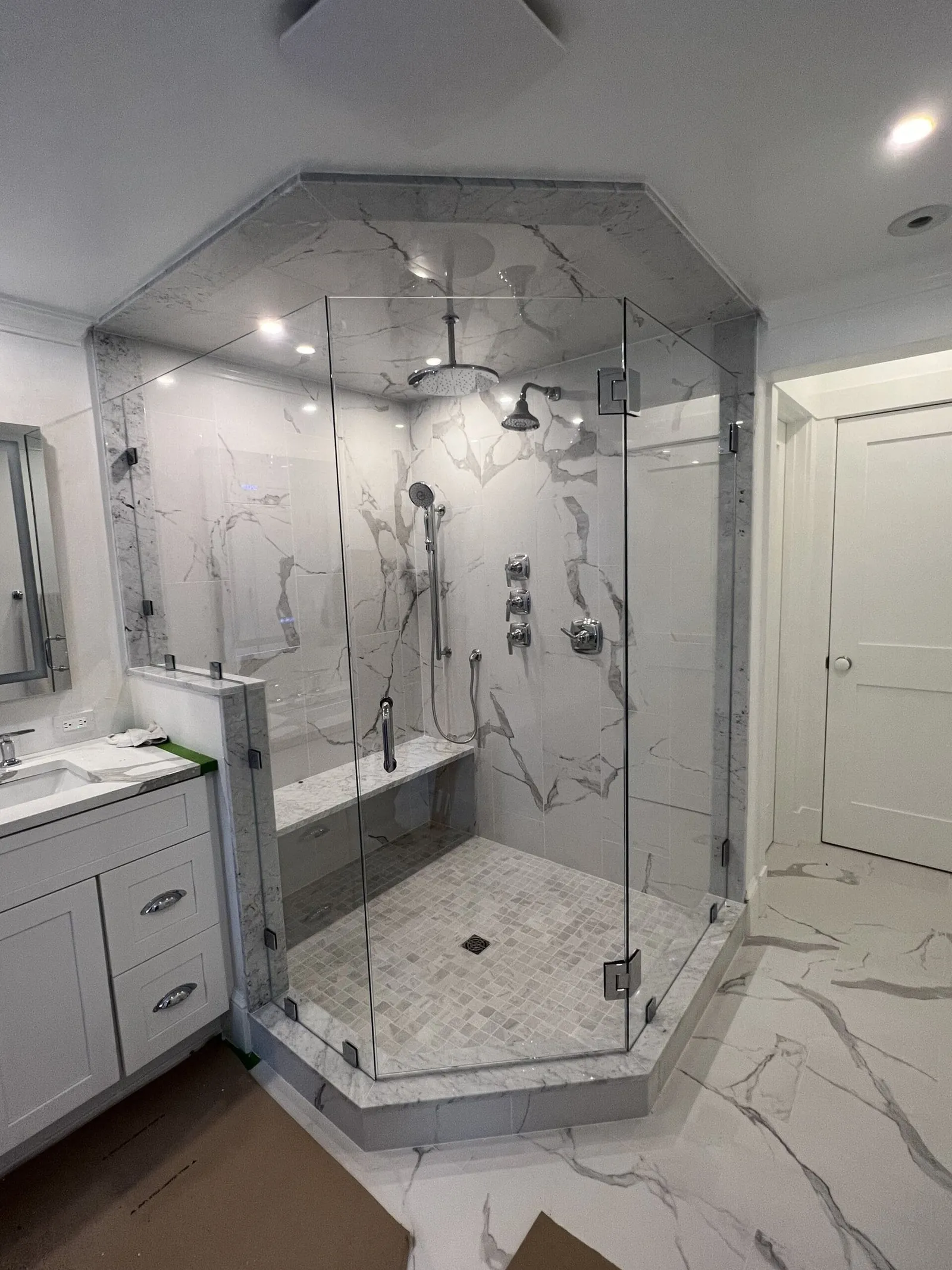 Neo-angle frameless glass shower with marble tile and black fixtures