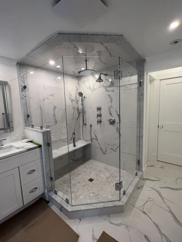 Marble-tiled glass shower enclosure with black fixtures