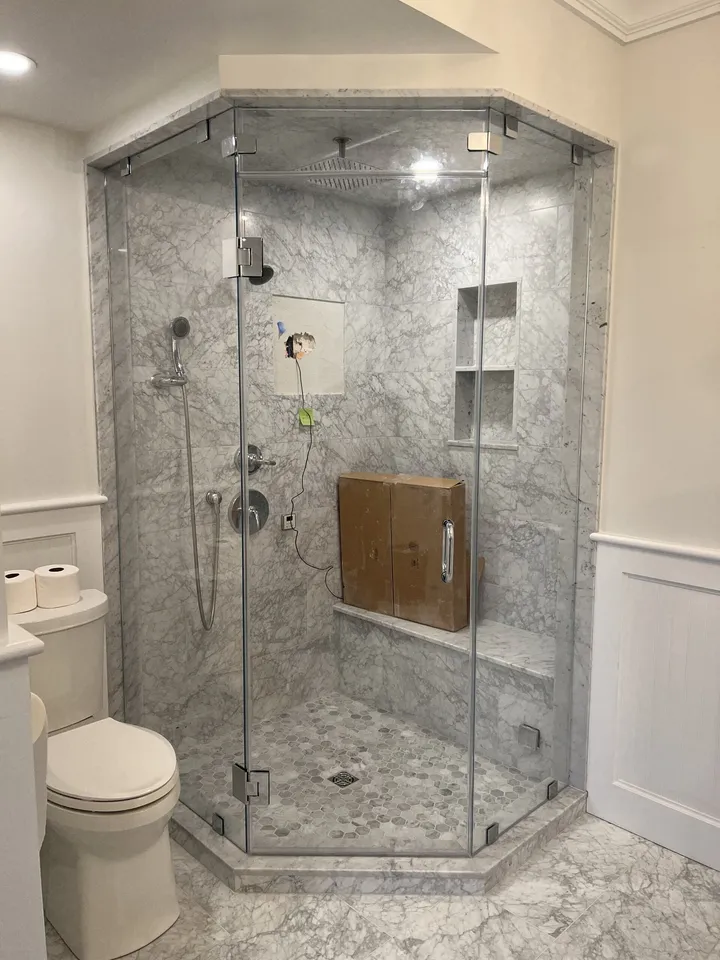 Marble shower enclosure with a frameless glass door