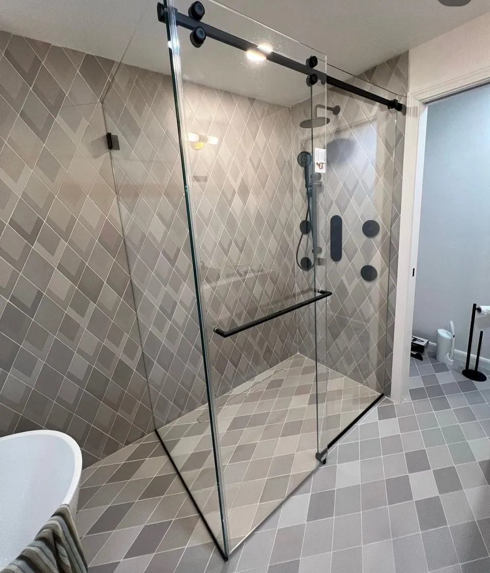 Sliding glass shower enclosure with black hardware installed by J.S Glazing LLC