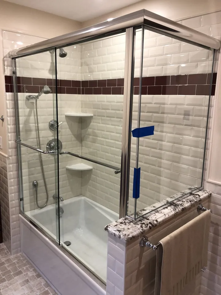 Sliding glass shower doors over a bathtub with white subway tile