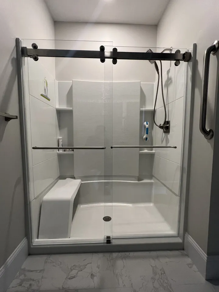 Sliding glass shower doors with matte black hardware and a seat