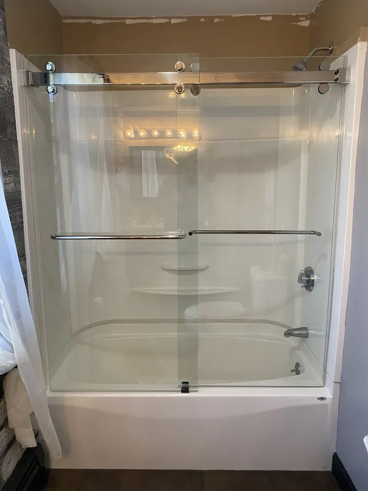 Glass shower enclosure over a white bathtub