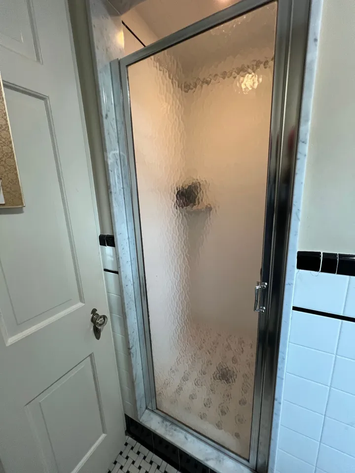 Textured glass framed shower door in a tiled alcove