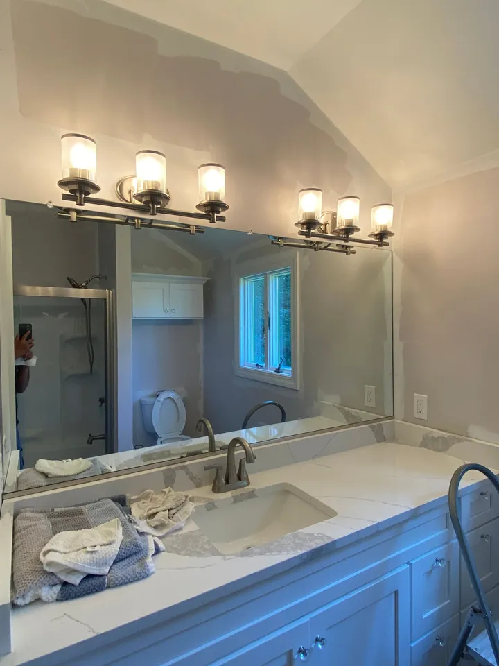 Large vanity mirror installed above a single sink with wall lights