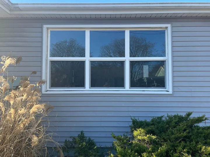 New white replacement window fitted in vinyl siding