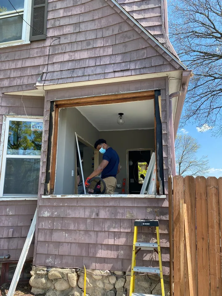 Window replacement in progress on a shingled home